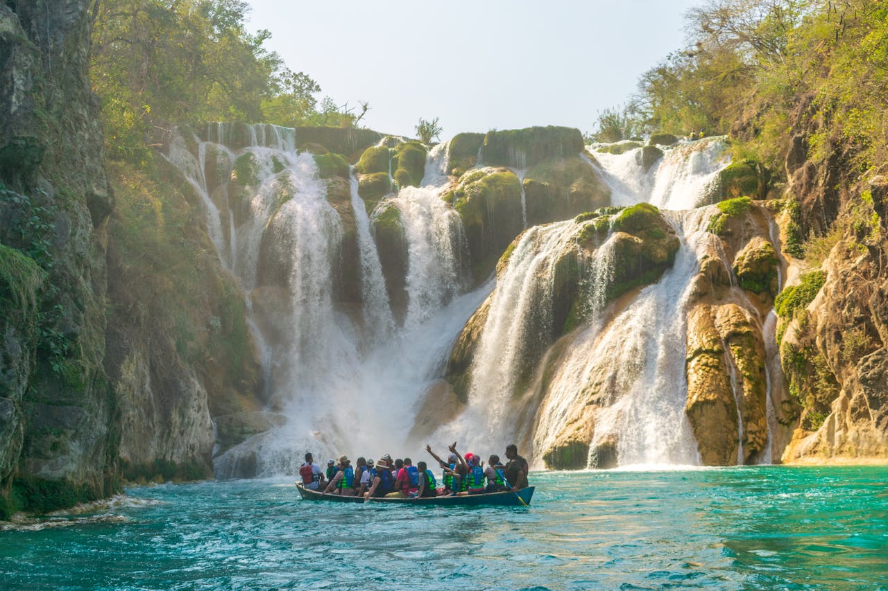 A boat navigates towards the majestic Tamul Waterfall in S.L.P., Mexico.