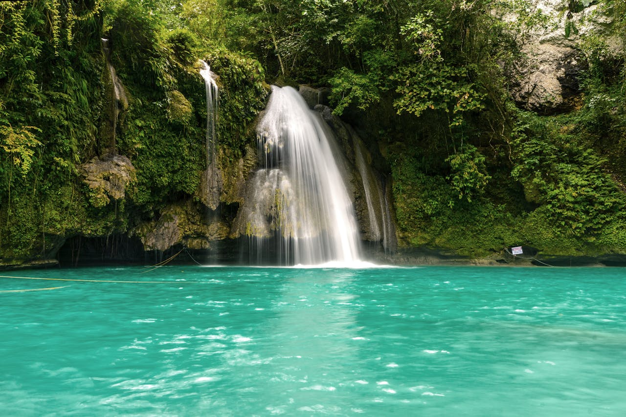 Capture of a stunning turquoise waterfall in a lush tropical setting, perfect for travel and nature enthusiasts.